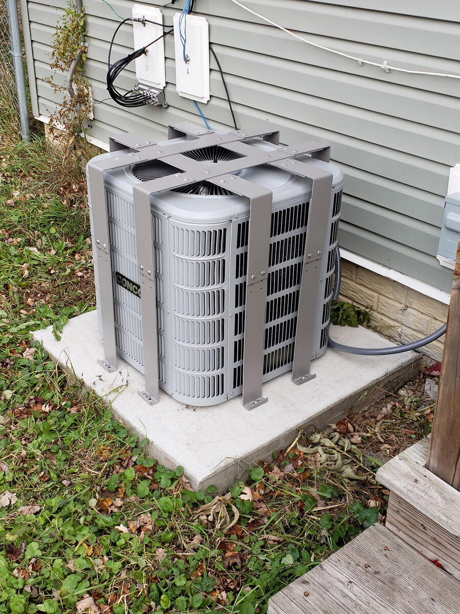 AC Bandit cage installed on a condenser near a home's electrical meter and deck
